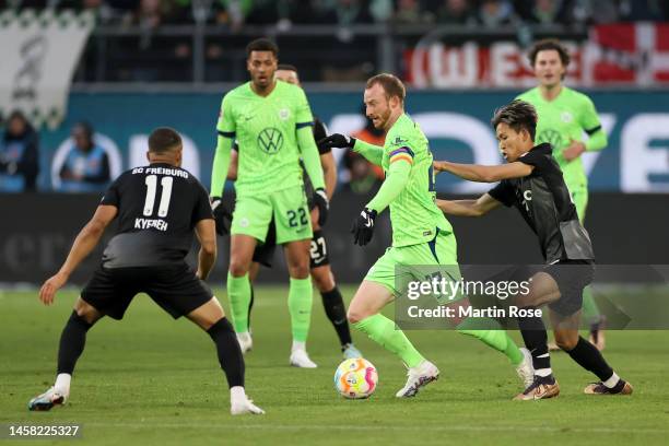 Maximilian Arnold of VfL Wolfsburg runs with the ball whilst under pressure from Daniel-Kofi Kyereh and Jeong Woo-Yeong of SC Freiburg during the...