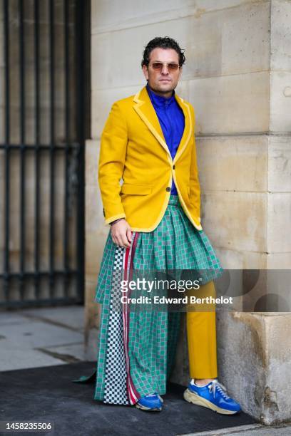 Guest wears yellow sunglasses, a royal blue zipper high neck jacket from Louis Vuitton, a yellow buttoned blazer jacket, a green and red checkered...