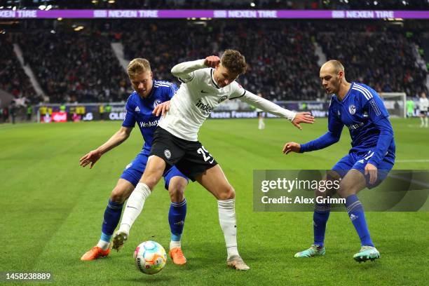 Jesper Lindstrom of Eintracht Frankfurt is challenged by Jere Uronen and Henning Matriciani of FC Schalke 04 during the Bundesliga match between...