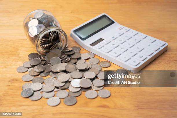 savings deposit coins in a clear glass bottle. coins in glass jar for money saving financial concept. calculator on office table - grass pile white background stock-fotos und bilder