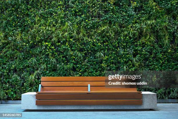 bench against plants decorated wall - environmental conservation stock pictures, royalty-free photos & images