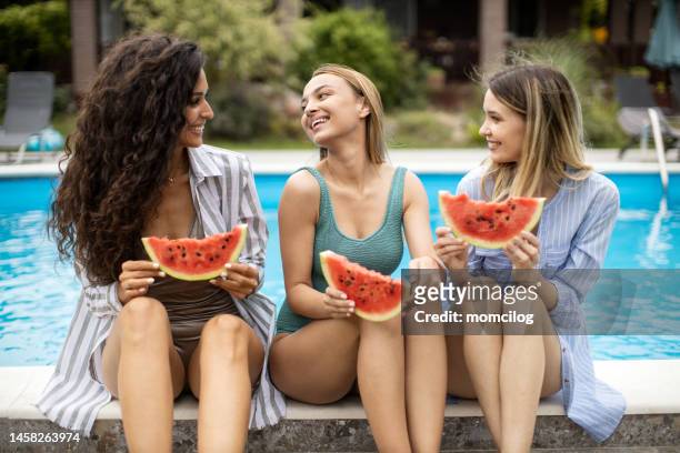 female friends having fun near the pool while eating watermelon - woman eating fruit imagens e fotografias de stock