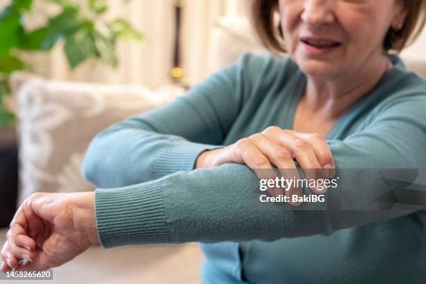 senior woman with pain at home - touching elbows stock pictures, royalty-free photos & images