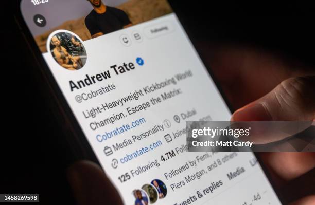 In this photo illustration a man looks at his phone displaying the social media Twitter page for Andrew Tate, on January 21, 2023 in Bath, England....