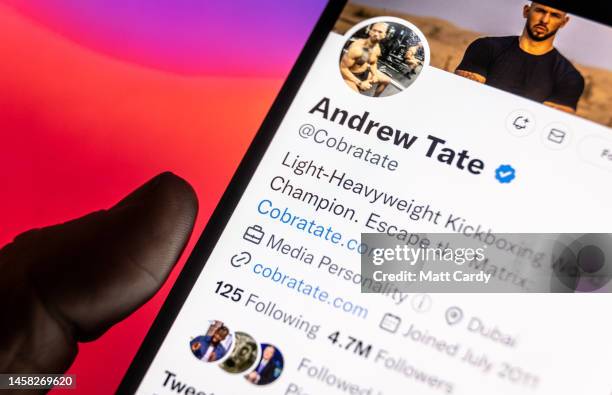 In this photo illustration a man looks at his phone displaying the social media Twitter page for Andrew Tate, on January 21, 2023 in Bath, England....