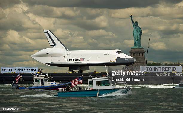 The space shuttle Enterprise is brought past the Statue of Liberty on a barge on June 6, 2012 in New York City. The shuttle is on it's way to the USS...