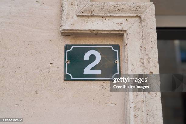 a cream-colored concrete wall with some holes and details on the edge and a green number two sign in white. - 2nd street stock pictures, royalty-free photos & images