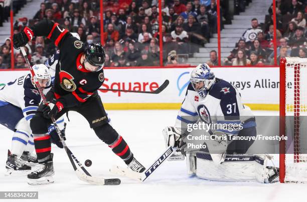 Brady Tkachuk of the Ottawa Senators battles for the loose puck with Connor Hellebuyck of the Winnipeg Jets during the second period at Canadian Tire...