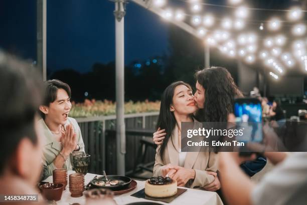 asian chinese lesbian couple celebrating birthday outdoor dining with friends - asian lesbians kiss stock pictures, royalty-free photos & images