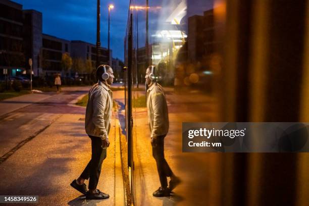 african american man in headphones boarding city bus at night, side view - bus side view stock pictures, royalty-free photos & images