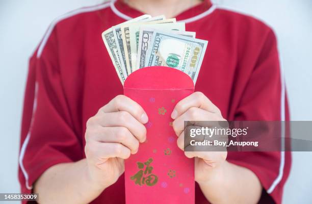 close up of woman holding a red envelope with american dollar banknotes in her hand. in chinese culture, the color red is associated with energy, happiness and good luck. - polymer banknote stock pictures, royalty-free photos & images