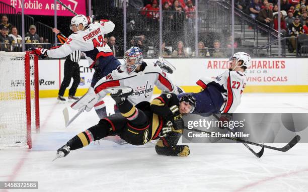 Jonas Rondbjerg of the Vegas Golden Knights and Alexander Alexeyev of the Washington Capitals fall to the ice as a shot by Byron Froese of the Vegas...