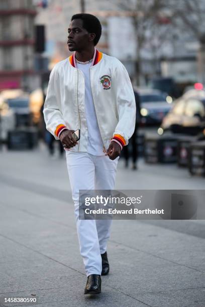 Guest wears a white and multicolored pearls necklace, a white t-shirt, a white with multicolored pearls logo embroidered pattern zipper bomber coat...