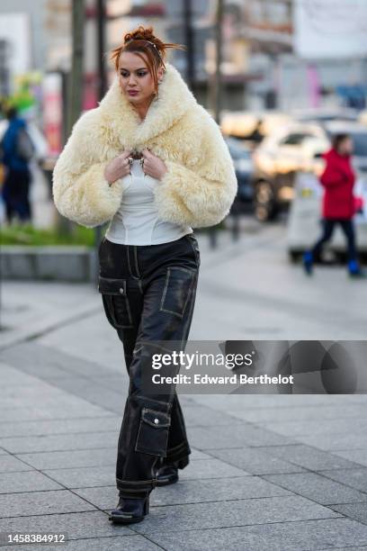 Guest wears silver hair clips, silver earrings, a white cut-out chest tank-top, a white latte oversized fur / fluffy cropped top, black cargo denim...