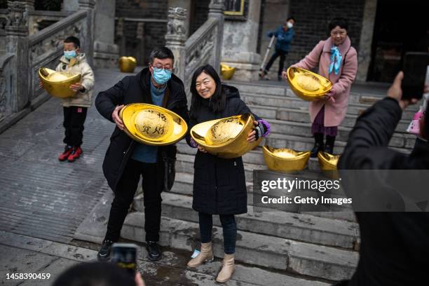 People hold models of gold ingots while posing for pictures in Expo Garden on January 22, 2023 in Wuhan, Hubei Province, China. China is marking the...