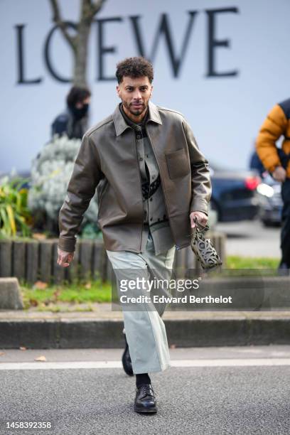 Guest wears a gray denim with embroidered brown fur strap pattern shirt from Loewe, a brown leather coat, a brown cut-out logo pattern tube handbag...