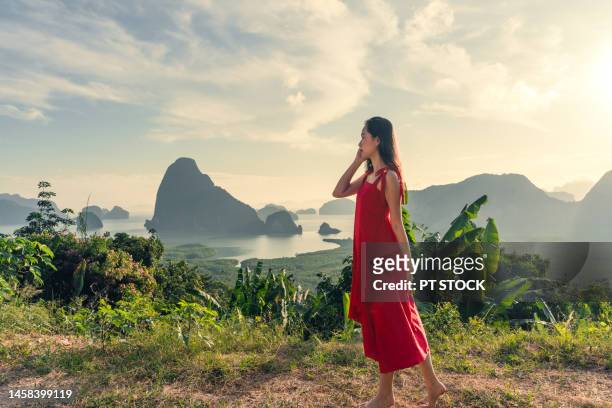 woman in red standing in view of sametnangshe phang nga bay with sea and mountains in phang nga province, thailand - red sea rain stock pictures, royalty-free photos & images