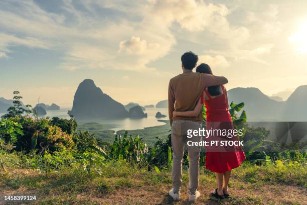 man and woman in red dress standing in hug like dancing in view of ao samet nang chee phang nga with sea and mountains in phang nga province, thailand - phuket province stock-fotos und bilder