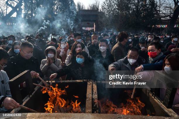 People light incense sticks in a cauldron before performing prayers for good fortune at Yonghegong, or the Lama Temple, for the Chinese Lunar New...