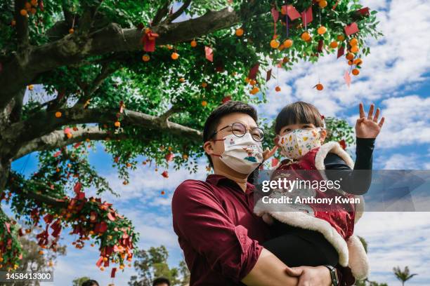 Man carrying his daughter poses for a photograph in front of the Wishing Tree at Lam Tsuen Village on January 22, 2023 in Hong Kong, China....