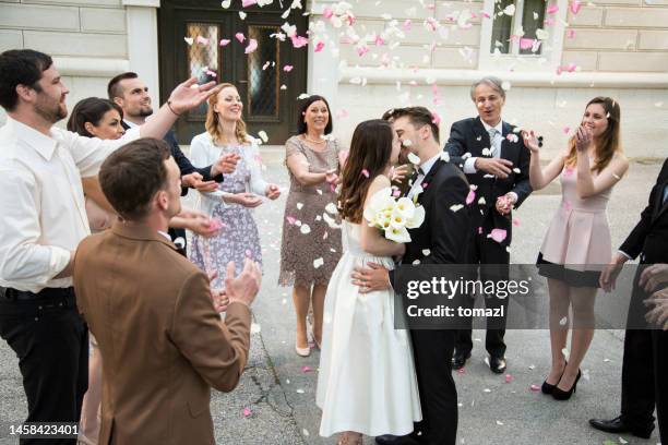 ospiti che lanciano petali di rosa su sposa e sposo baci - ricevimento formale foto e immagini stock