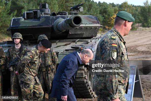 German Chancellor Olaf Scholz walks under the cannon of a Leopard 2 main battle tank of the Bundeswehr while visiting the Bundeswehr army training...