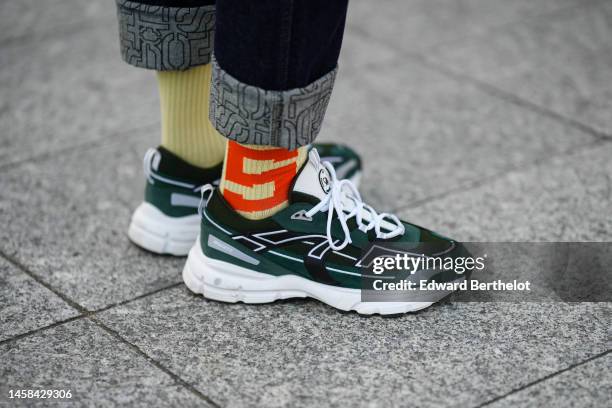 Guest wears black rolled-up denim pants, pale yellow and orange print pattern ribbed wool socks, black and dark green suede sneakers with white...