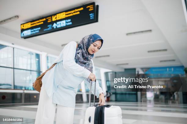 beautiful asian entrepreneur woman in the airport is going to have business travel, holding luggage - indonesian ethnicity stock pictures, royalty-free photos & images
