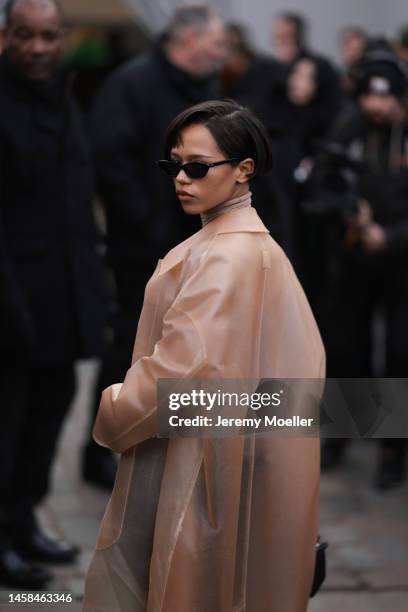 Taylor Russell seen wearing a transparent beige coat, beige brown turtleneck, black leather pants with silver details and a black handbag and black...