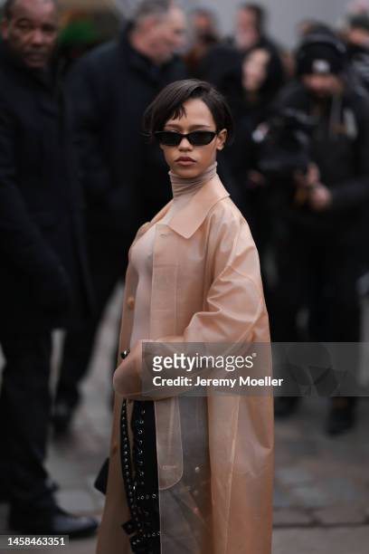 Taylor Russell seen wearing a transparent beige coat, beige brown turtleneck, black leather pants with silver details and a black handbag and black...