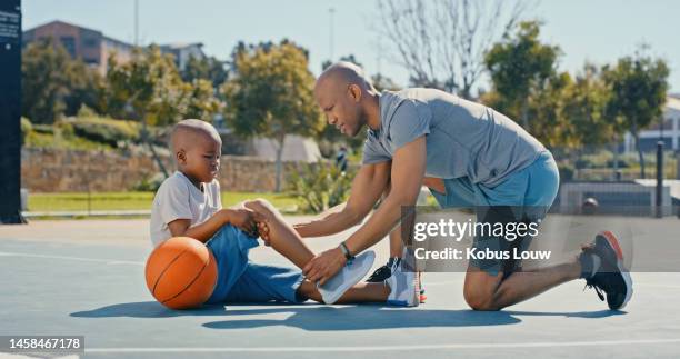 lesão esportiva ao ar livre com homem, criança e joelho lesionado com dor, acidente de basquete na quadra de basquete no parque. homem negro ajuda menino, emergência esportiva e verificar ferida com pai e filho com cuidado - knees together - fotografias e filmes do acervo