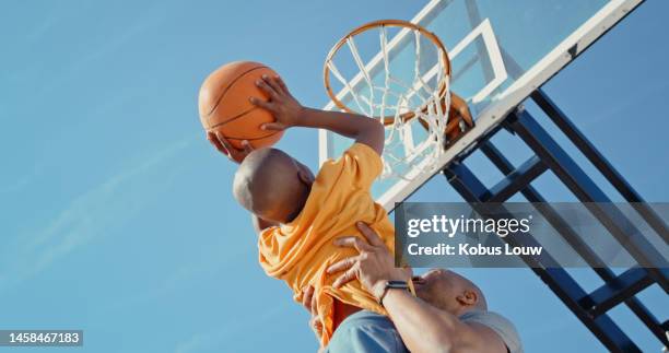 deportes, entrenamiento de baloncesto o práctica de tiro de padre e hijo, desafío de juego o competencia juvenil. cielo azul, unión de jugador de baloncesto o padre africano levantando a un niño, aprendiendo y jugando en el aro de la cancha - basket lift fotografías e imágenes de stock