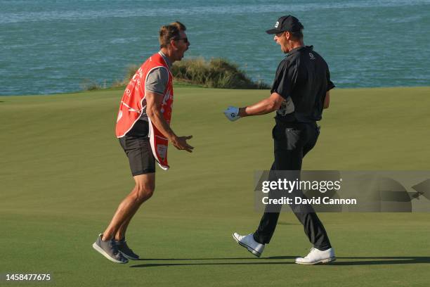 Victor Perez of France celebrates with his caddie James Erkenbeck after he had holed his second shot from the green-side bunker for a birdie 2 during...