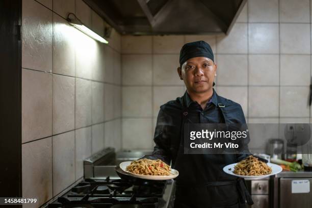 ein koch in schwarzer uniform bereitet eine mahlzeit zu. - chef smelling food stock-fotos und bilder