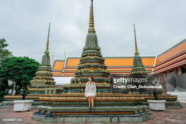 woman sitting near pagoda in   wat pho temple in bangkok - sabbatical stockfoto's en -beelden
