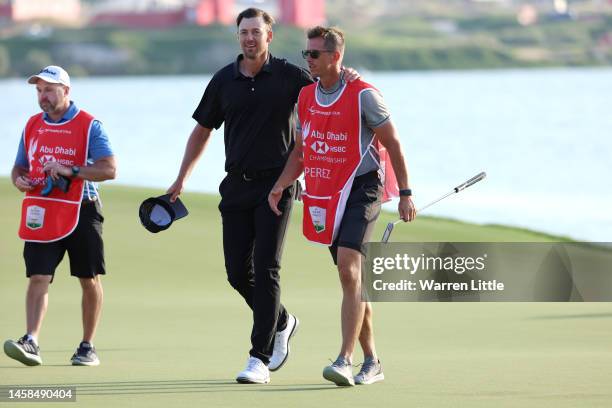 Victor Perez of France celebrates after finishing his round on the eighteenth green with his caddie, James Erkenbeck during day four of the Abu Dhabi...
