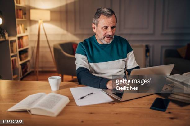 male writer with beard uses laptop, working late - authors night 個照片及圖片檔