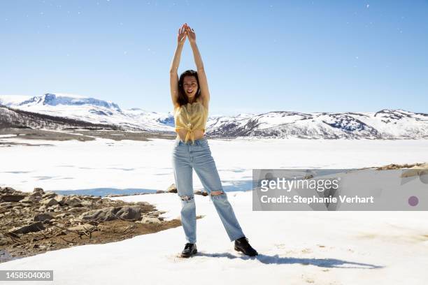 woman standing in snow on a warm spring day in norway - winter and sun stockfoto's en -beelden