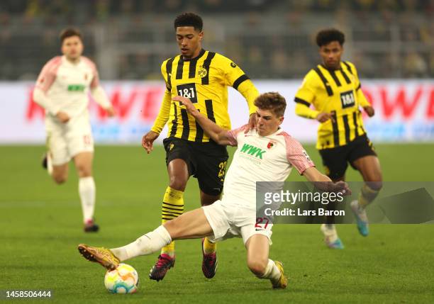 Jude Bellingham of Borussia Dortmund is challenged by Arne Engels of FC Augsburg during the Bundesliga match between Borussia Dortmund and FC...
