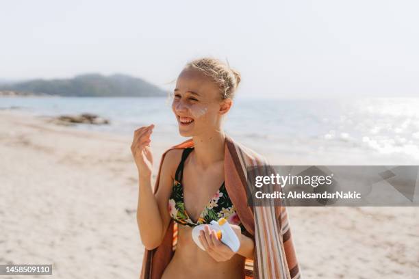 teenager trägt sonnencreme am strand auf - girls sunbathing stock-fotos und bilder