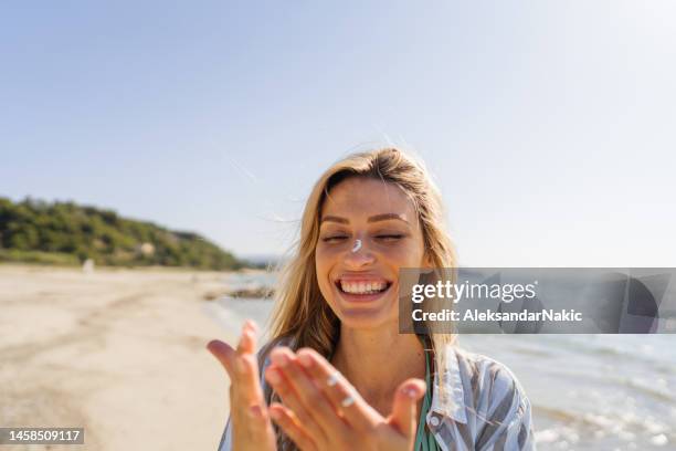 junge frau, die sonnencreme am strand aufträgt - spf 30 stock-fotos und bilder