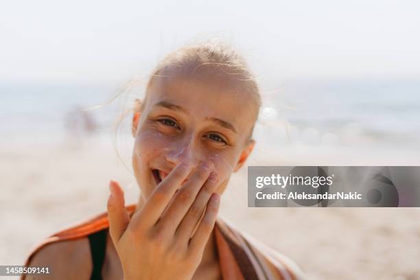 teenage girl applying sunscreen at the beach - sun on face stock pictures, royalty-free photos & images