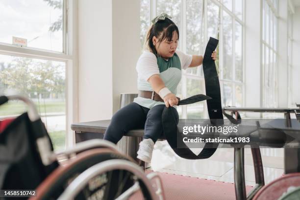 young disabled woman in wheelchair preparing to train in gym. - little people stock pictures, royalty-free photos & images