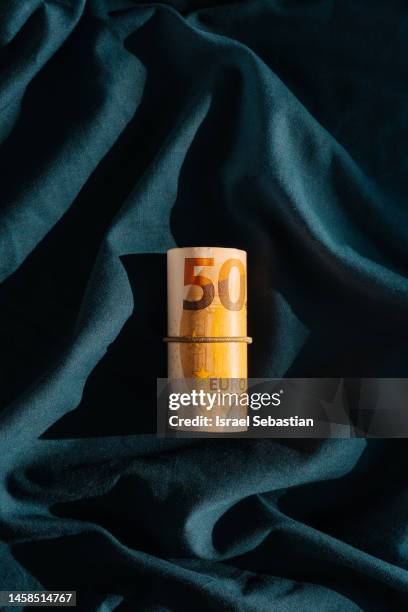bundle of fifty euro bills on a dark blue background. - fajo de billetes de euro fotografías e imágenes de stock