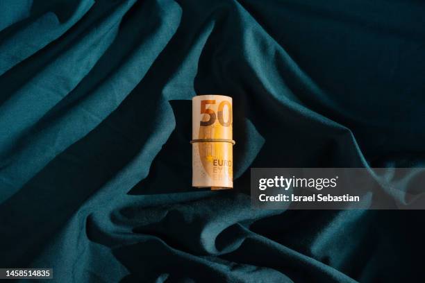 bundle of 50 euro bills on a dark blue background. - fajo de billetes de euro fotografías e imágenes de stock