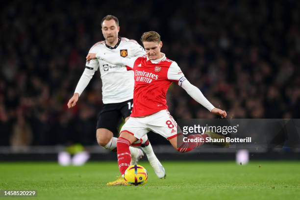 Martin Odegaard of Arsenal is challenged by Christian Eriksen of Manchester United during the Premier League match between Arsenal FC and Manchester...