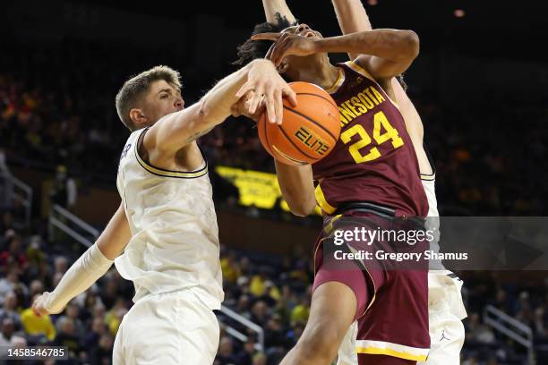 Jaden Henley of the Minnesota Golden Gophers has his shot blocked while driving to the basket by Joey Baker of the Michigan Wolverines during the...