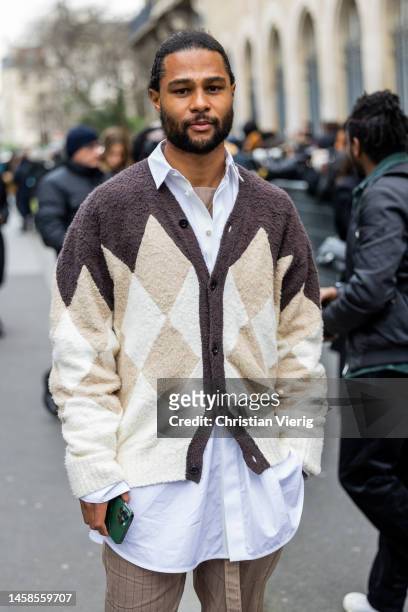 Serge Gnabry wears brown pants, cardigan, white button shirt outside Sacai during Paris Fashion Week - Menswear Fall-Winter 2023-2024 on January 22,...