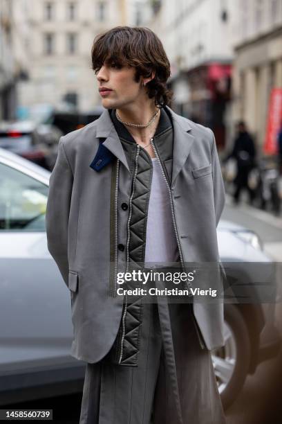 Guest wears grey blazer, pants with sl outside Sacai during Paris Fashion Week - Menswear Fall-Winter 2023-2024 on January 22, 2023 in Paris, France.