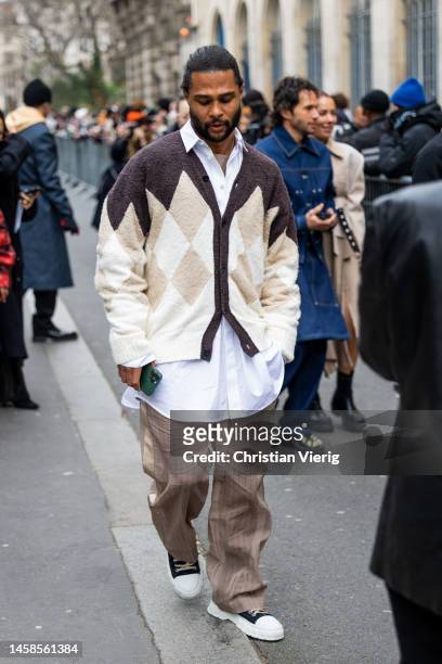 Serge Gnabry wears brown pants, cardigan, white button shirt outside Sacai during Paris Fashion Week - Menswear Fall-Winter 2023-2024 on January 22,...